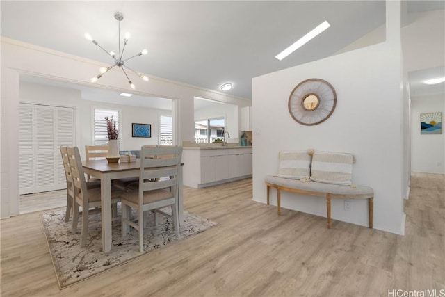 dining space with light hardwood / wood-style floors, sink, lofted ceiling, and a chandelier