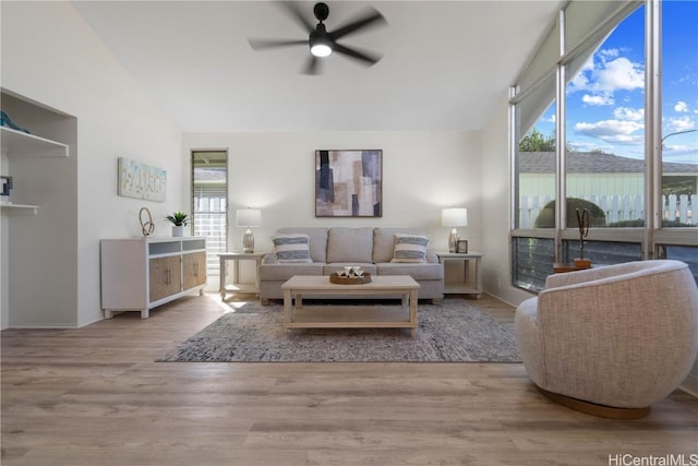 living room featuring light hardwood / wood-style floors, a wealth of natural light, ceiling fan, and a fireplace