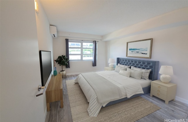 bedroom featuring light hardwood / wood-style flooring and an AC wall unit