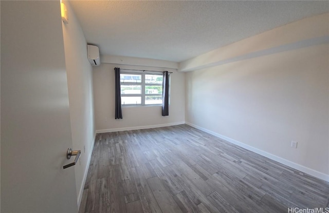 unfurnished room featuring a textured ceiling, dark hardwood / wood-style floors, and an AC wall unit