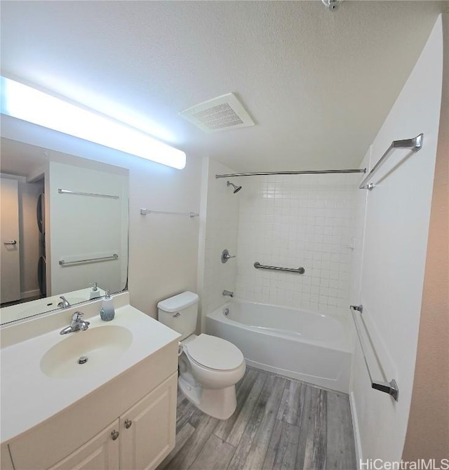 full bathroom with toilet, tiled shower / bath combo, hardwood / wood-style flooring, a textured ceiling, and vanity