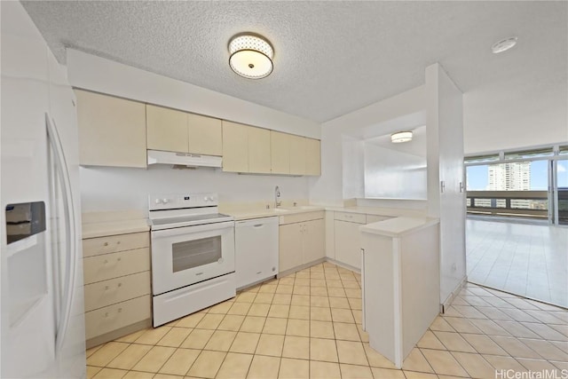 kitchen featuring light tile patterned floors, cream cabinetry, white appliances, a textured ceiling, and sink