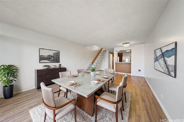500 University Ave Unit 2406, Honolulu, HI 96826 - dining space with baseboards, a textured ceiling, light wood-style floors, and stairs