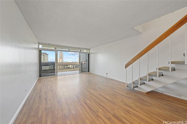 interior space with a textured ceiling, floor to ceiling windows, and light hardwood / wood-style floors