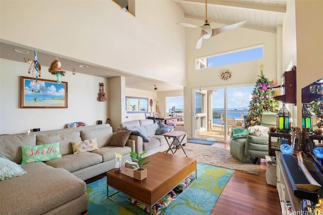 living room with ceiling fan, hardwood / wood-style floors, beam ceiling, high vaulted ceiling, and a water view