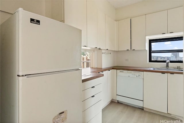 kitchen with wooden counters, sink, white appliances, light hardwood / wood-style flooring, and white cabinets