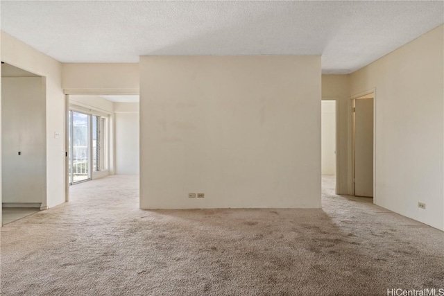 empty room with a textured ceiling and light carpet