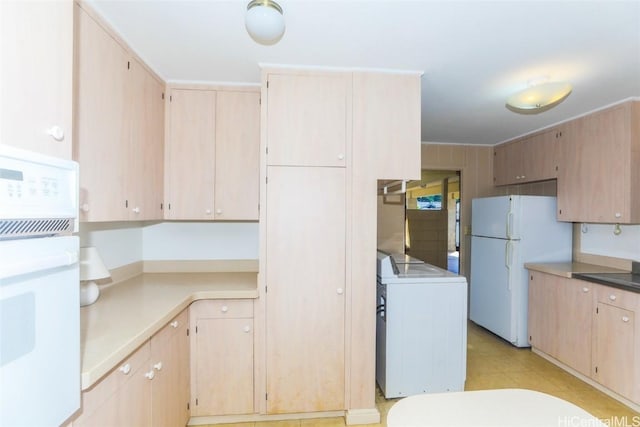 kitchen with white appliances, light brown cabinets, and washer / dryer