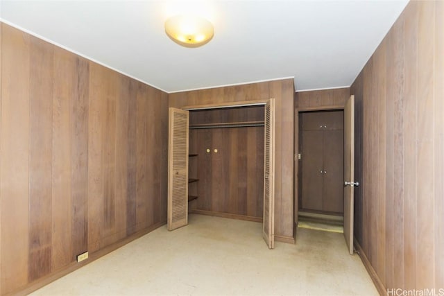 unfurnished bedroom with a closet and wooden walls