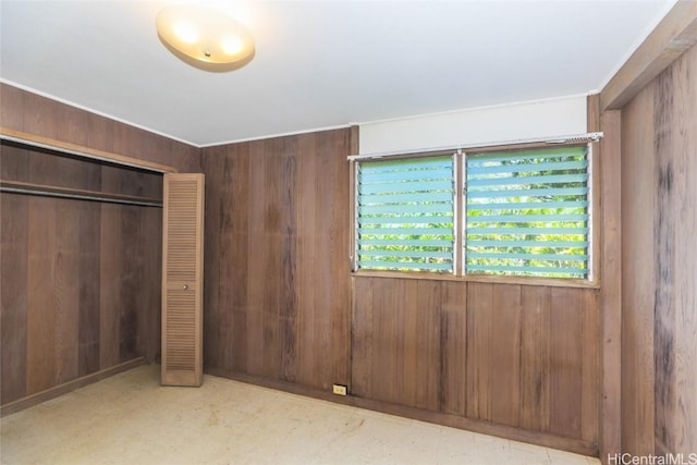 unfurnished bedroom with a closet and wooden walls