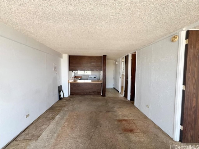 hallway with light carpet and a textured ceiling