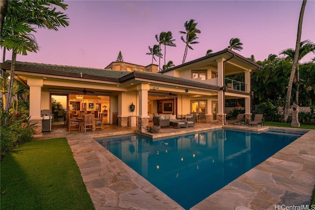 pool at dusk with an outdoor pool, an outdoor living space, a ceiling fan, and a patio