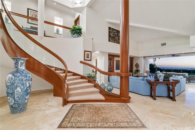 staircase with visible vents and high vaulted ceiling