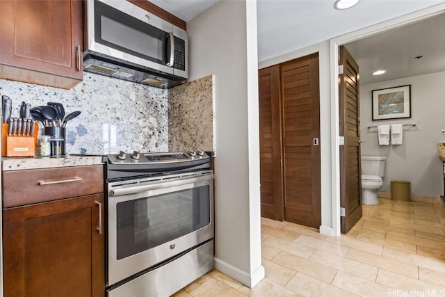 kitchen with tasteful backsplash, light countertops, appliances with stainless steel finishes, light tile patterned flooring, and baseboards