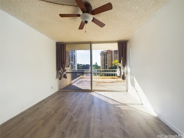 empty room featuring hardwood / wood-style flooring, a textured ceiling, expansive windows, and ceiling fan