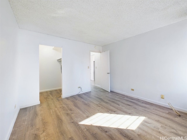 unfurnished room with a textured ceiling and light wood-type flooring