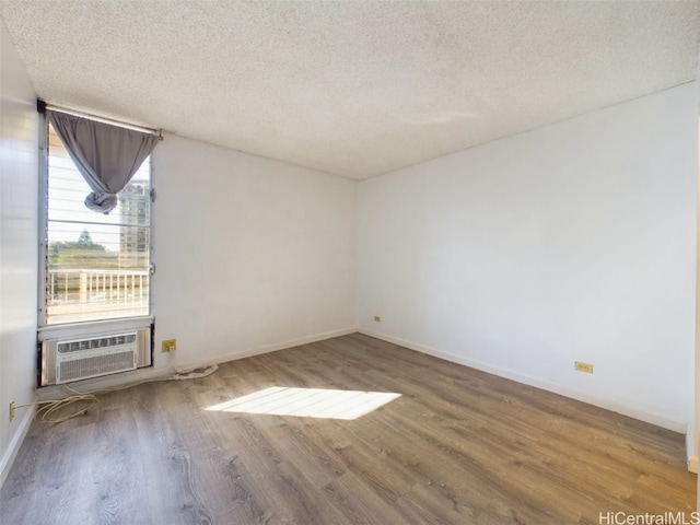 unfurnished room with wood-type flooring, a textured ceiling, and cooling unit