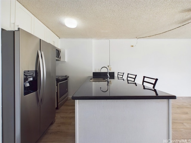 kitchen featuring stainless steel appliances, dark hardwood / wood-style floors, a textured ceiling, white cabinets, and sink