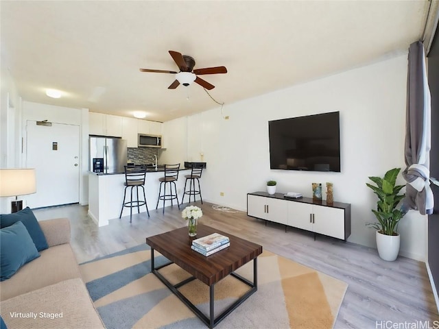 living room with ceiling fan, sink, and light hardwood / wood-style floors