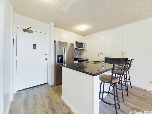 kitchen featuring white cabinets, kitchen peninsula, appliances with stainless steel finishes, and a textured ceiling