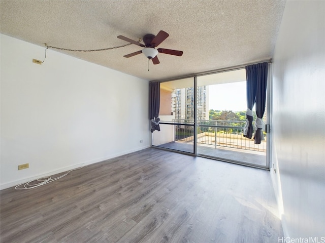 spare room with ceiling fan, hardwood / wood-style flooring, a textured ceiling, and a wall of windows