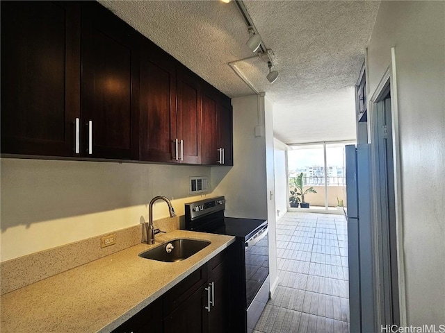 kitchen featuring stainless steel range with electric stovetop, a textured ceiling, track lighting, expansive windows, and sink