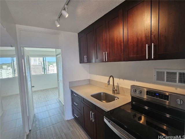 kitchen with a textured ceiling, stainless steel electric stove, track lighting, light tile patterned floors, and sink