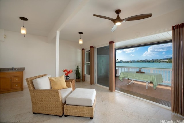 living area with ceiling fan, a water view, and sink