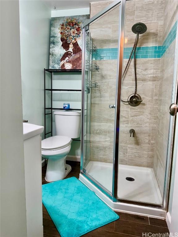 bathroom featuring a shower with door and toilet