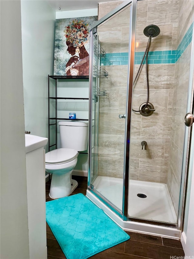 bathroom with a shower stall, toilet, and wood finished floors