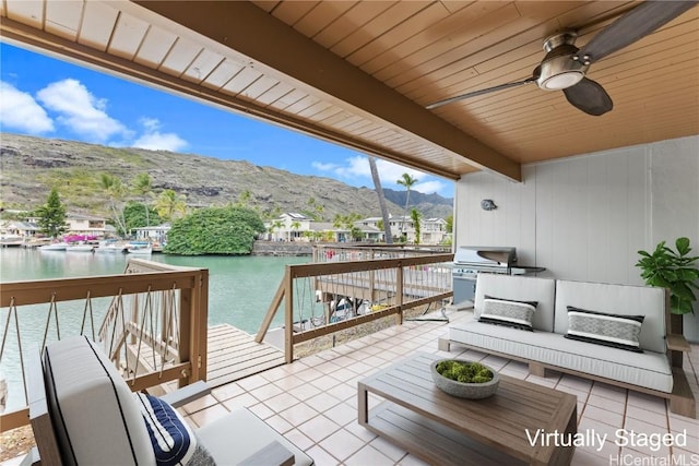 view of patio / terrace with a water and mountain view, ceiling fan, a grill, and an outdoor living space