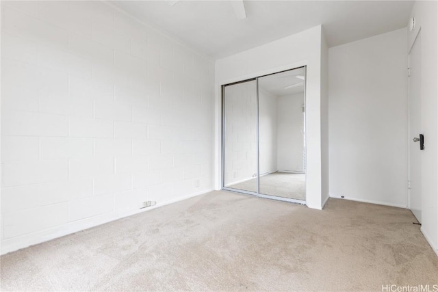 unfurnished bedroom featuring ceiling fan, a closet, and light carpet