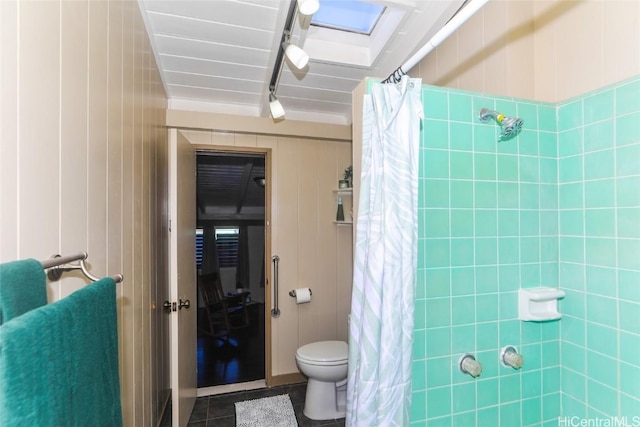 bathroom with toilet, tile patterned flooring, a skylight, and walk in shower