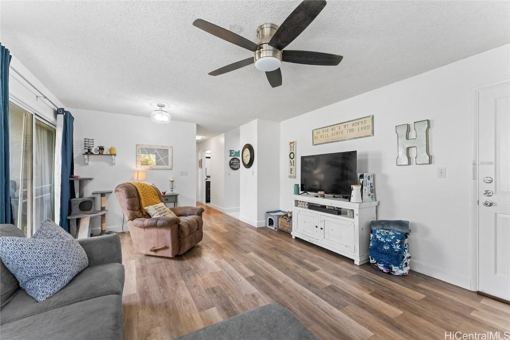 living room featuring ceiling fan, a textured ceiling, and hardwood / wood-style flooring