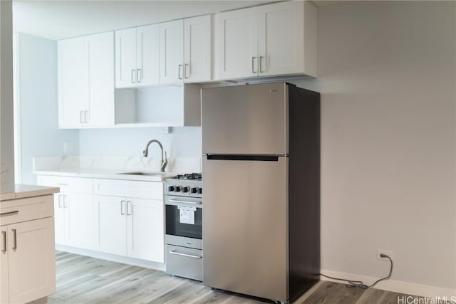 kitchen featuring sink, appliances with stainless steel finishes, light hardwood / wood-style flooring, and white cabinetry