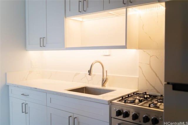 kitchen featuring sink, white cabinetry, gas stove, and light stone countertops