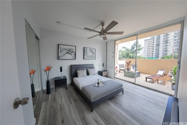 bedroom featuring ceiling fan, a wall of windows, wood-type flooring, and access to exterior