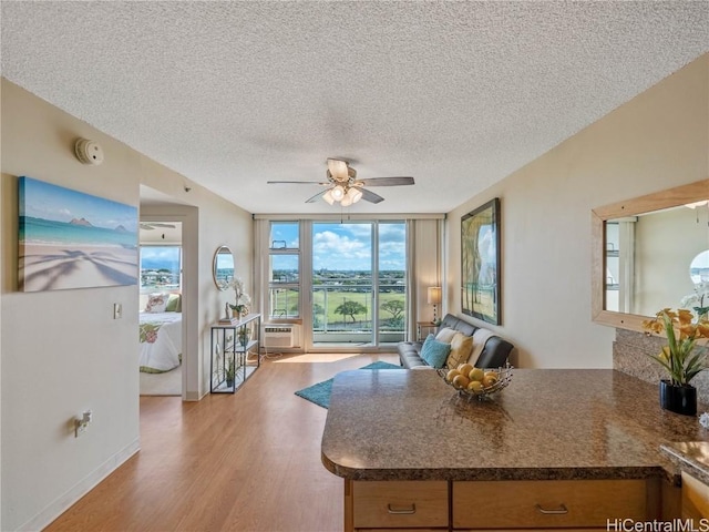 kitchen featuring ceiling fan, floor to ceiling windows, kitchen peninsula, light wood-type flooring, and a textured ceiling