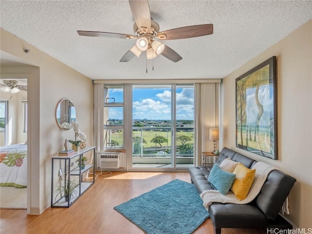 sitting room featuring light hardwood / wood-style floors, a textured ceiling, expansive windows, and ceiling fan