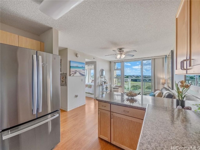 kitchen with ceiling fan, light hardwood / wood-style floors, light brown cabinets, a textured ceiling, and stainless steel fridge