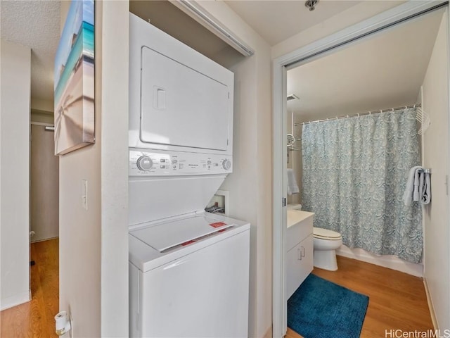 clothes washing area featuring light hardwood / wood-style flooring and stacked washing maching and dryer