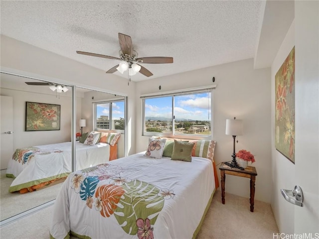 bedroom with ceiling fan, multiple windows, light carpet, and a textured ceiling