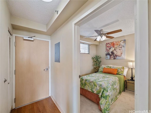 bedroom featuring a textured ceiling, ceiling fan, electric panel, and light hardwood / wood-style flooring