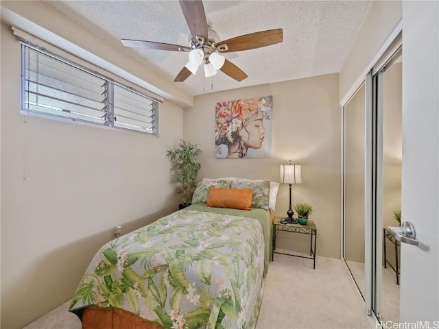 bedroom with ceiling fan, a closet, light carpet, and a textured ceiling