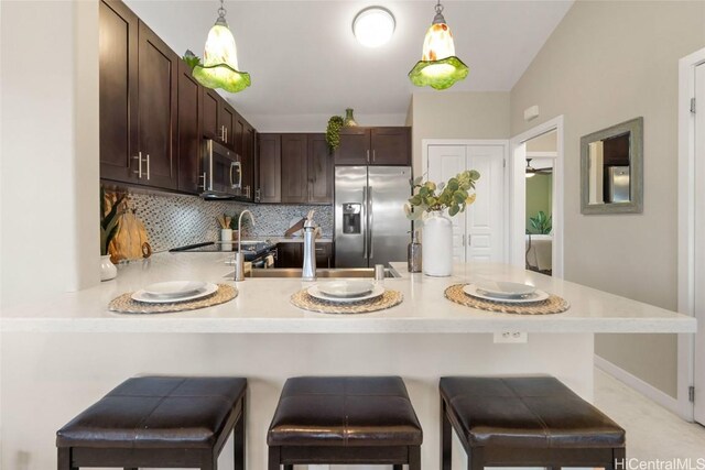 kitchen featuring appliances with stainless steel finishes, a breakfast bar area, dark brown cabinetry, and kitchen peninsula