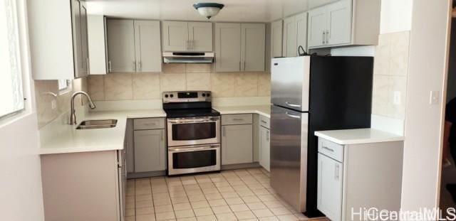 kitchen featuring gray cabinets, decorative backsplash, sink, light tile patterned flooring, and stainless steel appliances