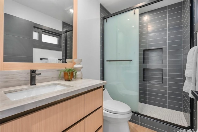 bathroom featuring toilet, a shower with shower door, and vanity