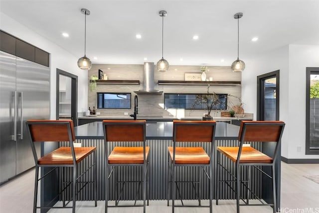 kitchen featuring a kitchen bar, stainless steel built in refrigerator, and pendant lighting