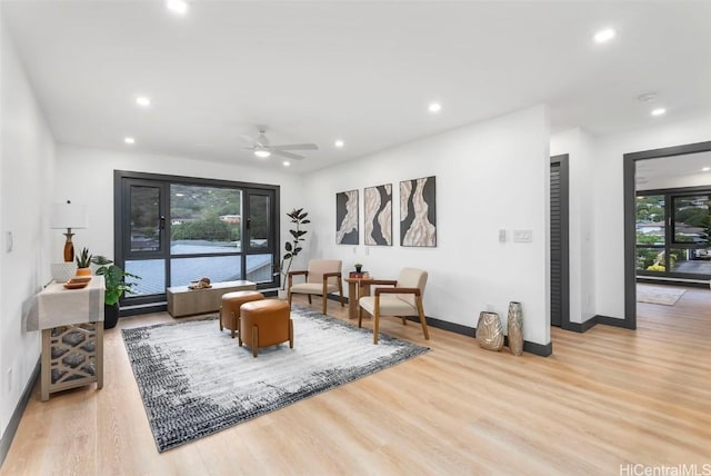 living room with ceiling fan and light hardwood / wood-style flooring