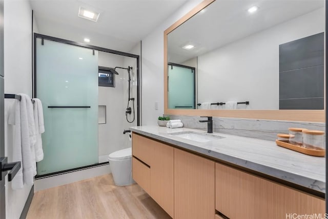 bathroom with toilet, vanity, wood-type flooring, and an enclosed shower